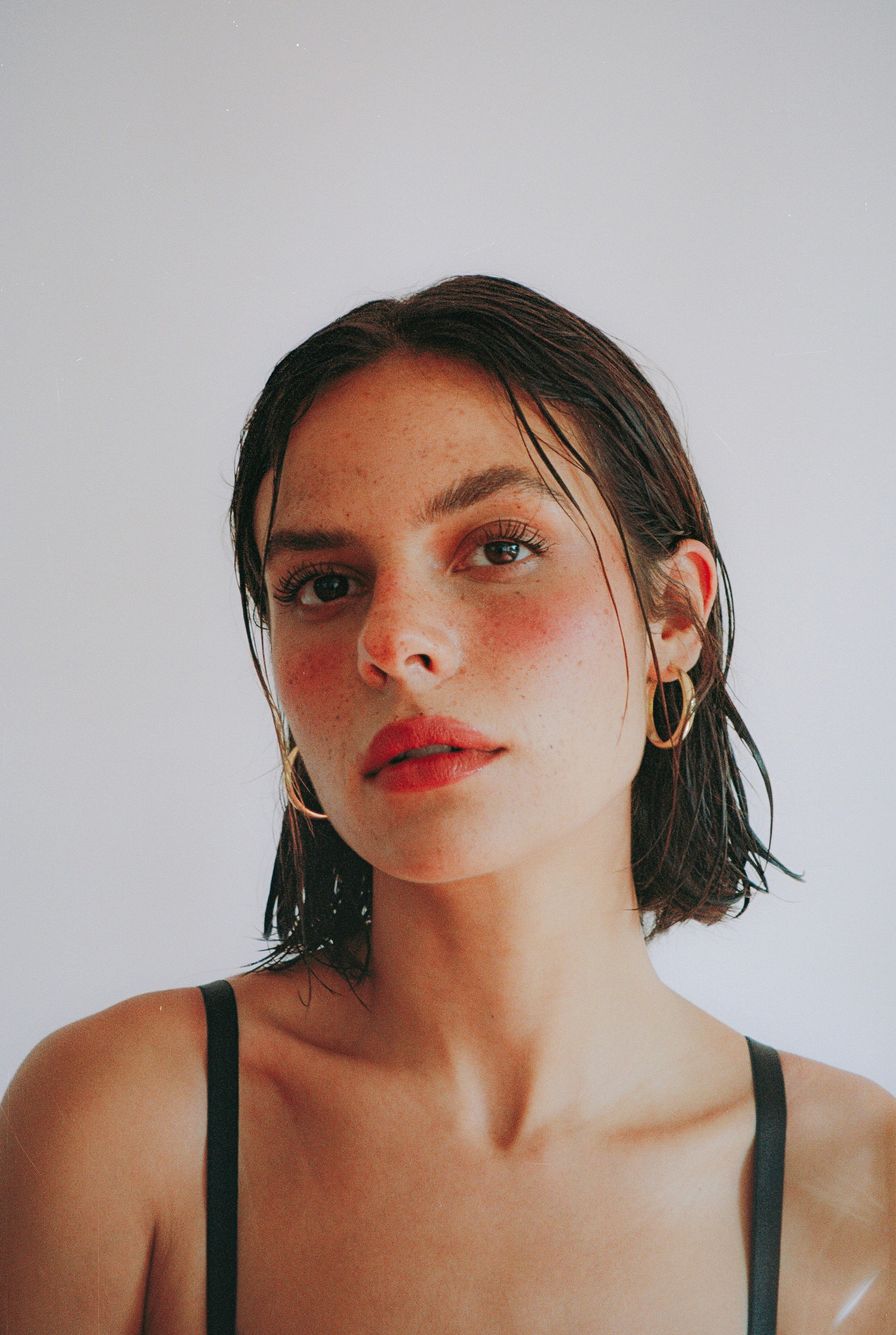 Young woman with freckles and gold earrings
