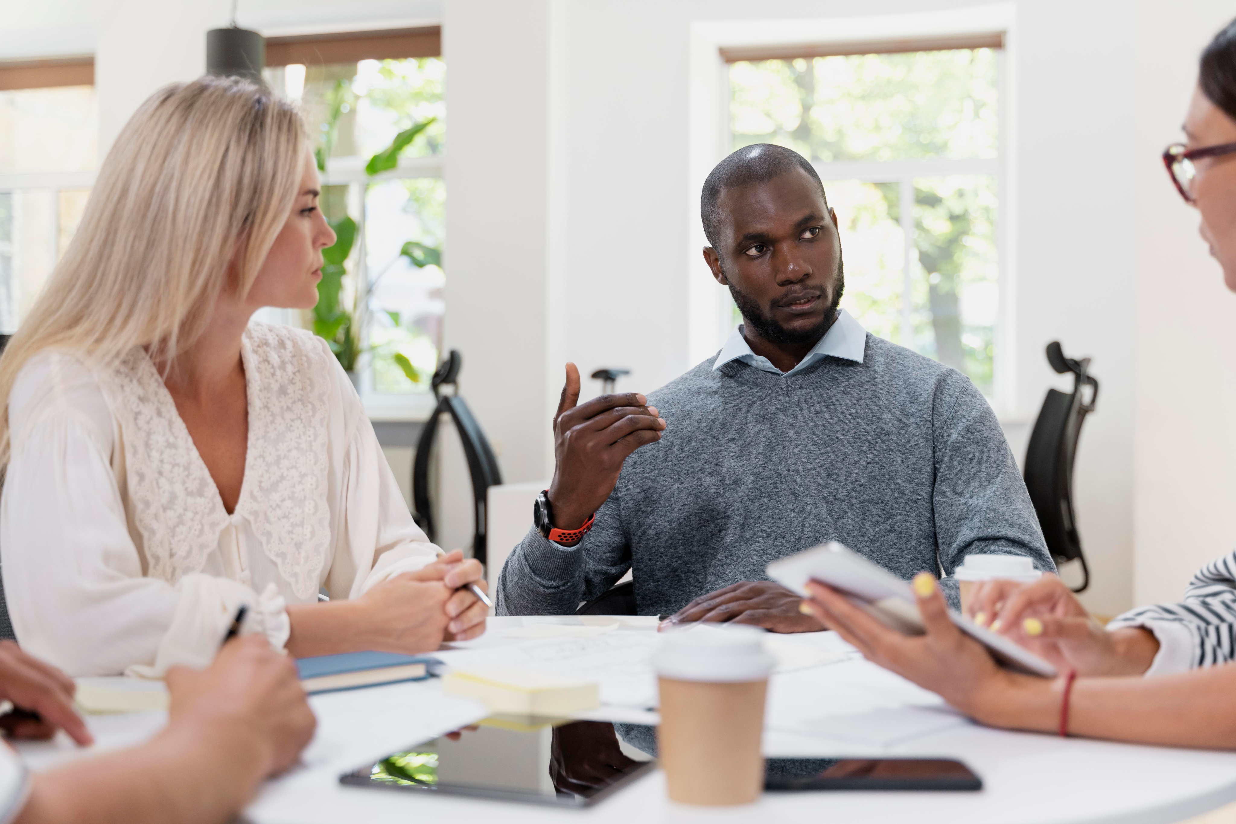 Team collaboration meeting with diverse professionals discussing around a table
