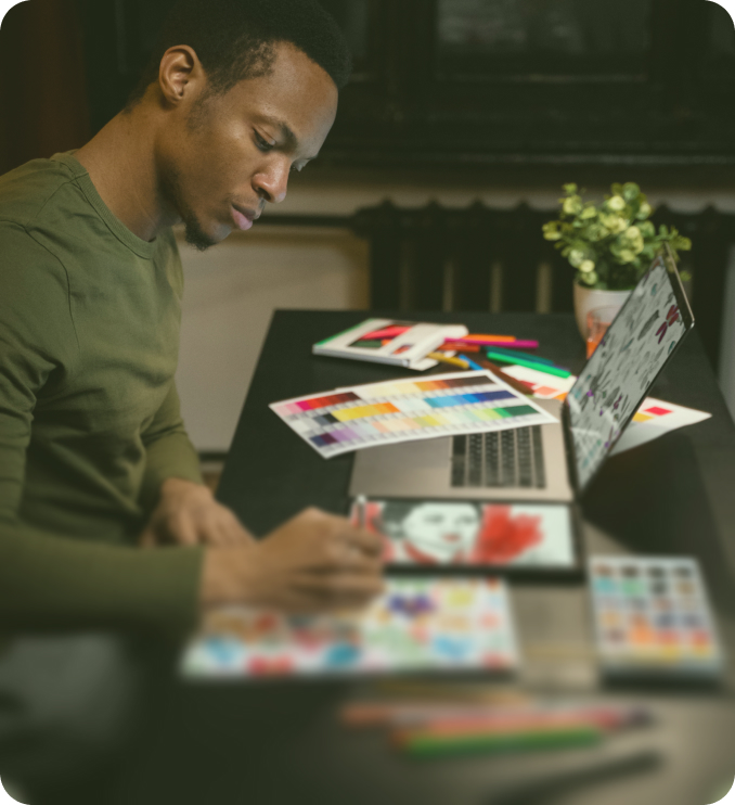 Young creative designer working at desk with tablet and laptop